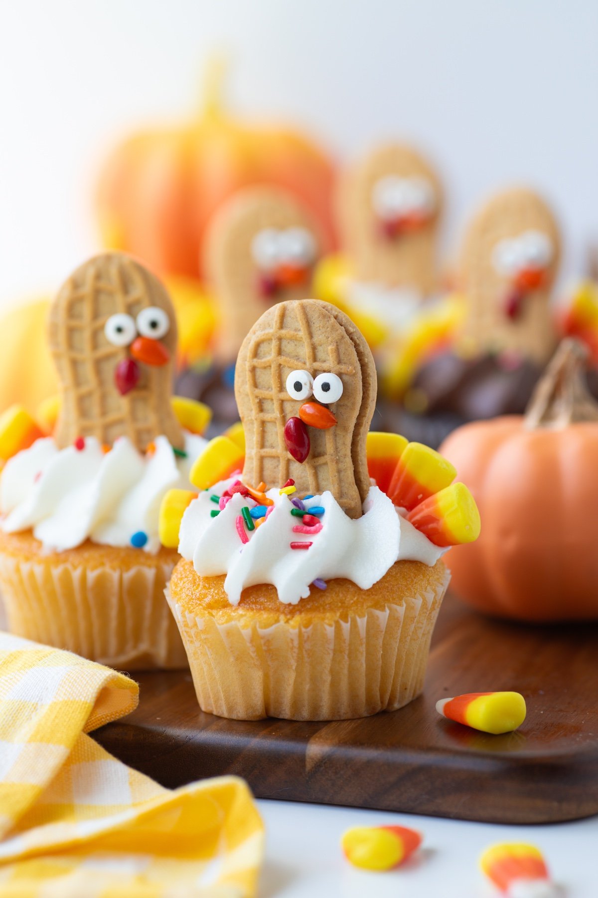 vanilla frosted turkey cupcakes on a wooden serving board. 