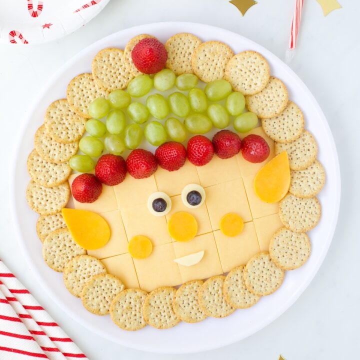 Elf cheese tray with crackers grapes and strawberries.