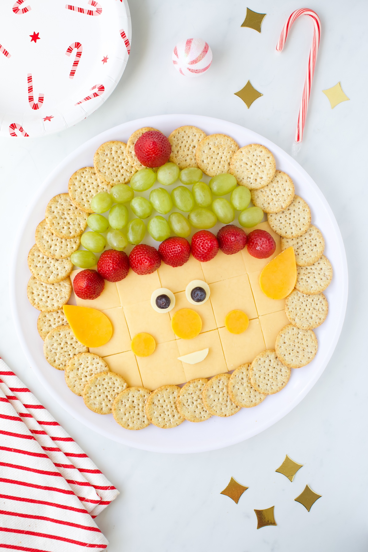 Elf cheese tray with crackers grapes and strawberries.