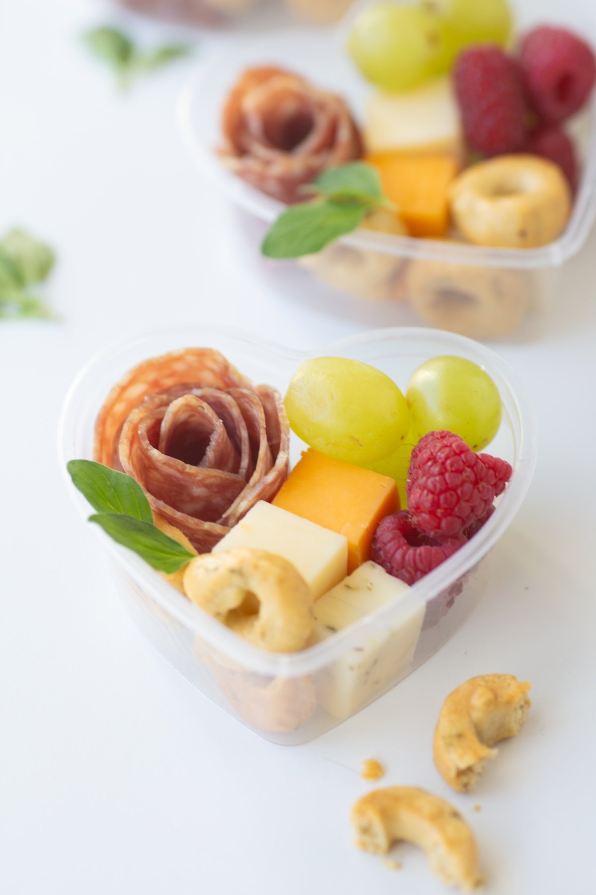 A close-up of the perfect Mini Heart Charcuterie Box stacked with succulent strawberries, creamy cheeses, and salami.