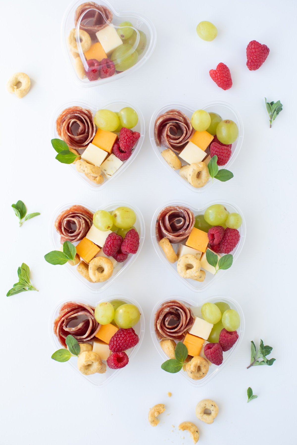 A beautifully arranged Mini Heart Charcuterie Box filled with vibrant fruits, rich chocolates, artisan cheeses, and perfectly sliced salami. A gourmet treat for the eyes and the palate.