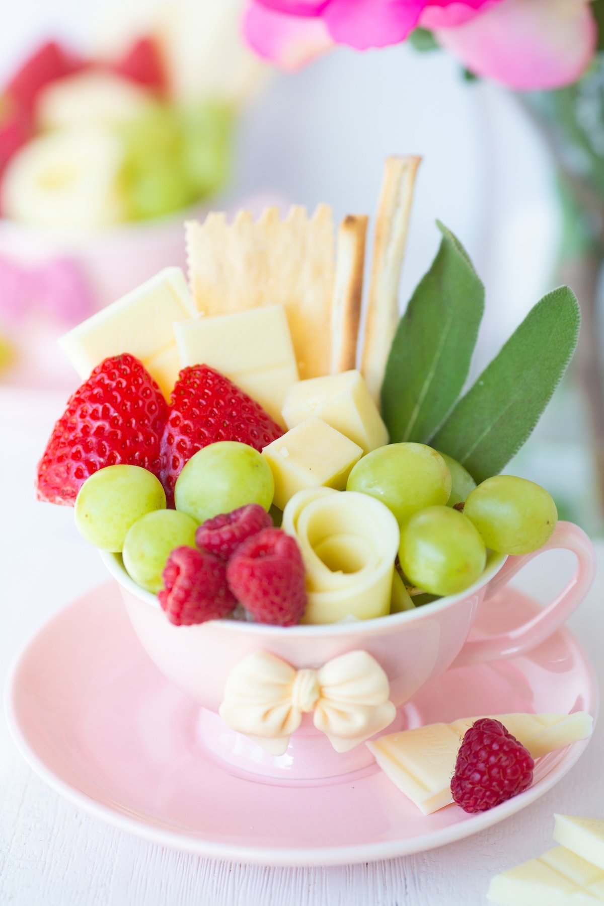 charcuterie tea cups with fruit, crackers and sweets. pretty bow teacups.