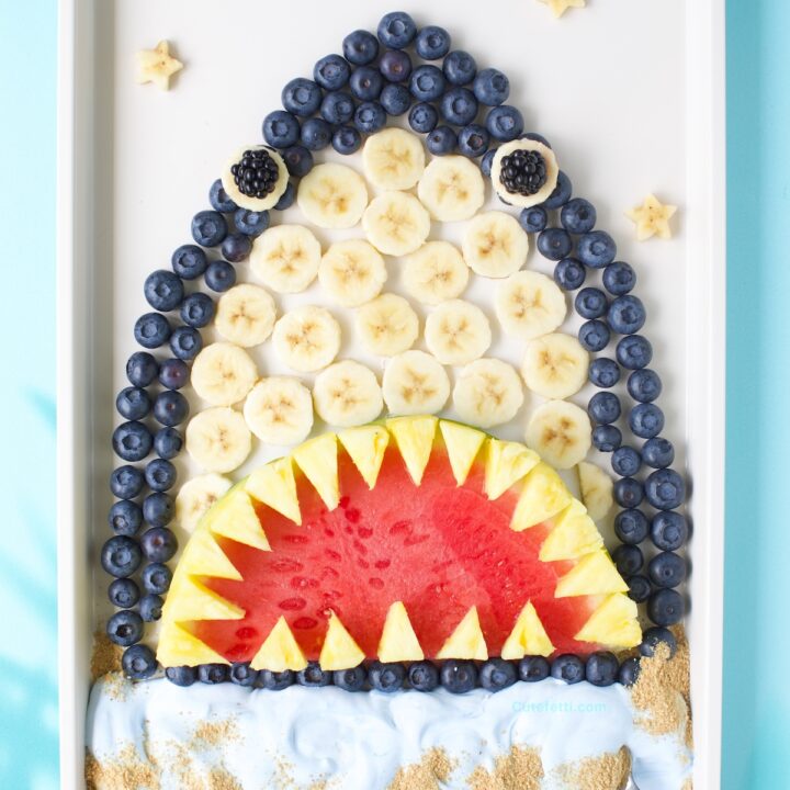 Fruit shark fruit tray, sharkcuterie board with blue-tinted whipped topping.