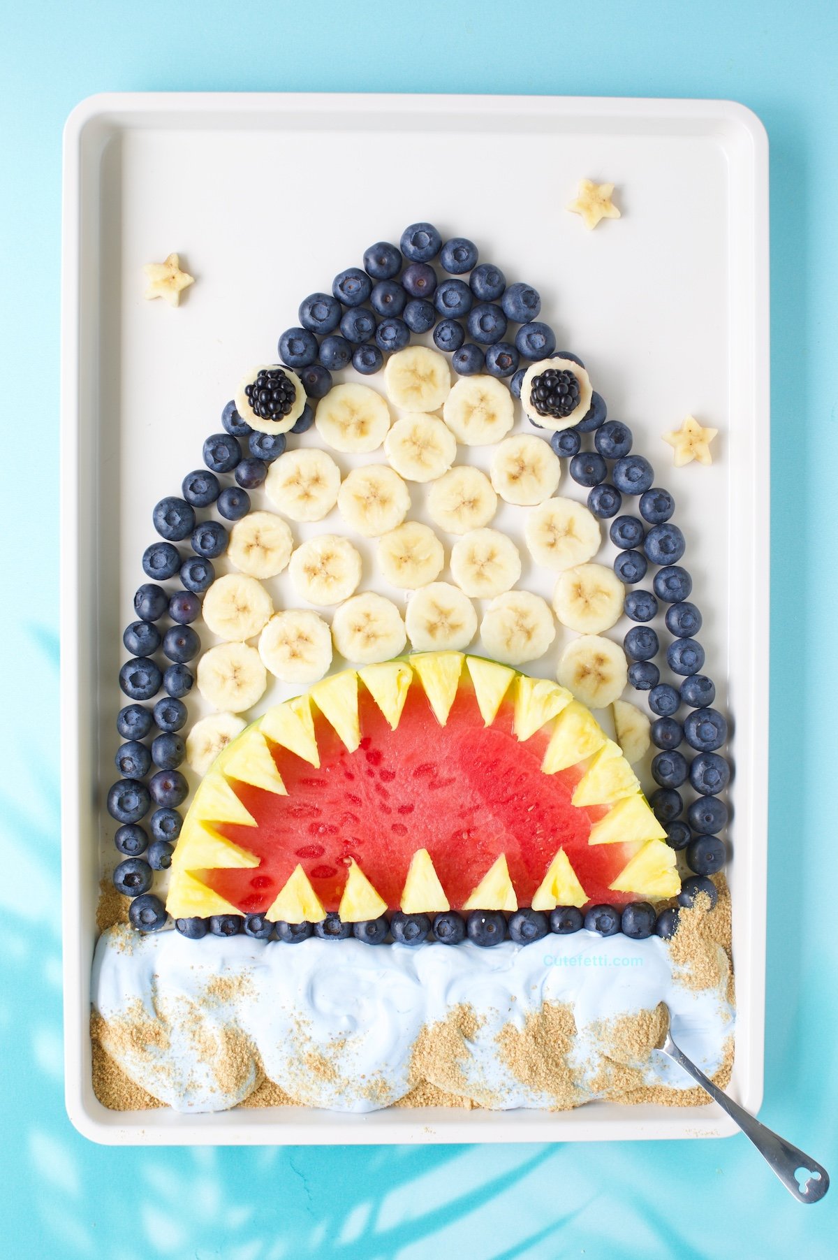 Fruit shark fruit tray, sharkcuterie board with blue-tinted whipped topping.