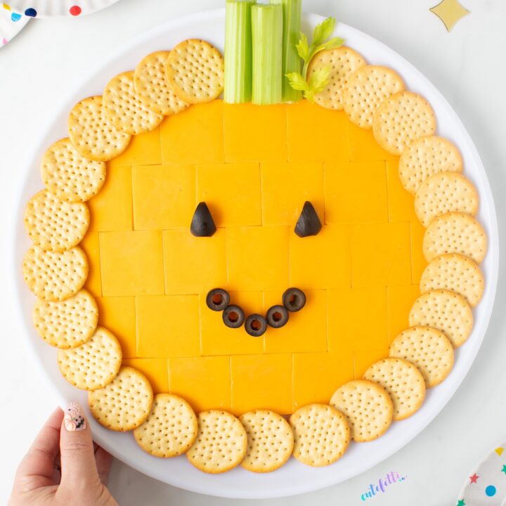 pumpkin cheese tray with cheddar cracker cuts, crackers, celery and black olives.