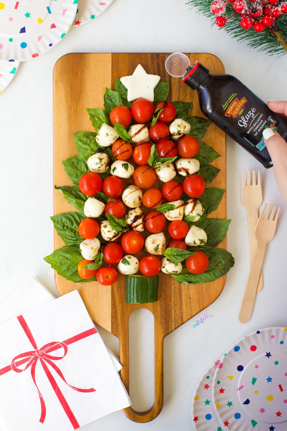 Christmas Tree Caprese on a wooden serving board along with balsamic glaze