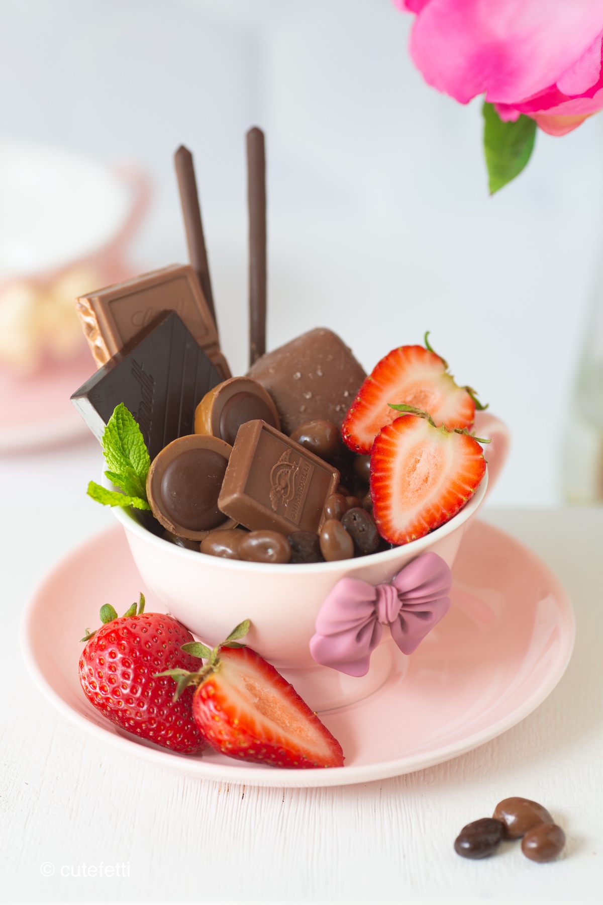 chocolate snack cups filled with a variety of chocolate candies and bars and strawberries and mint.