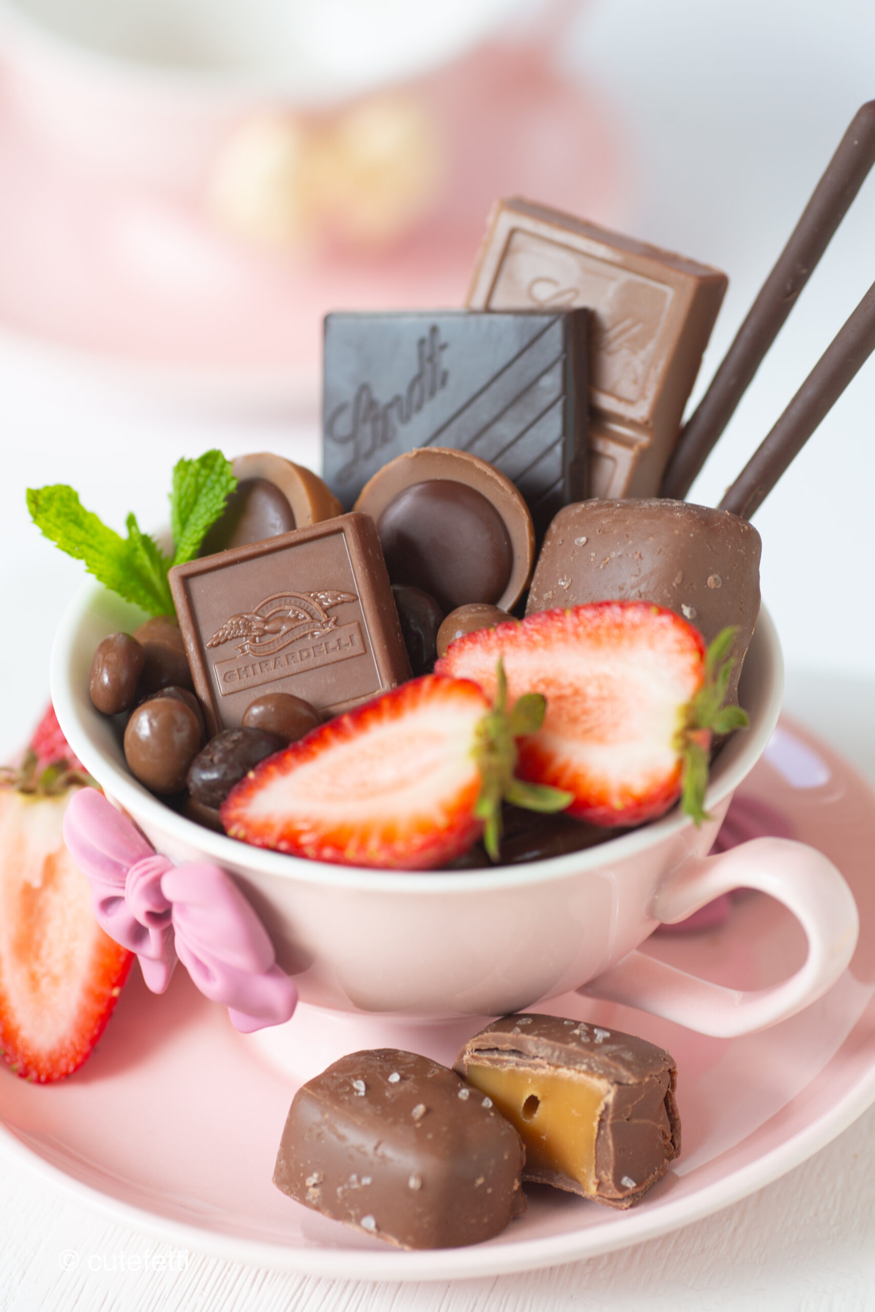 up close teacup dessert charcuterie with chocolate and sliced strawberries