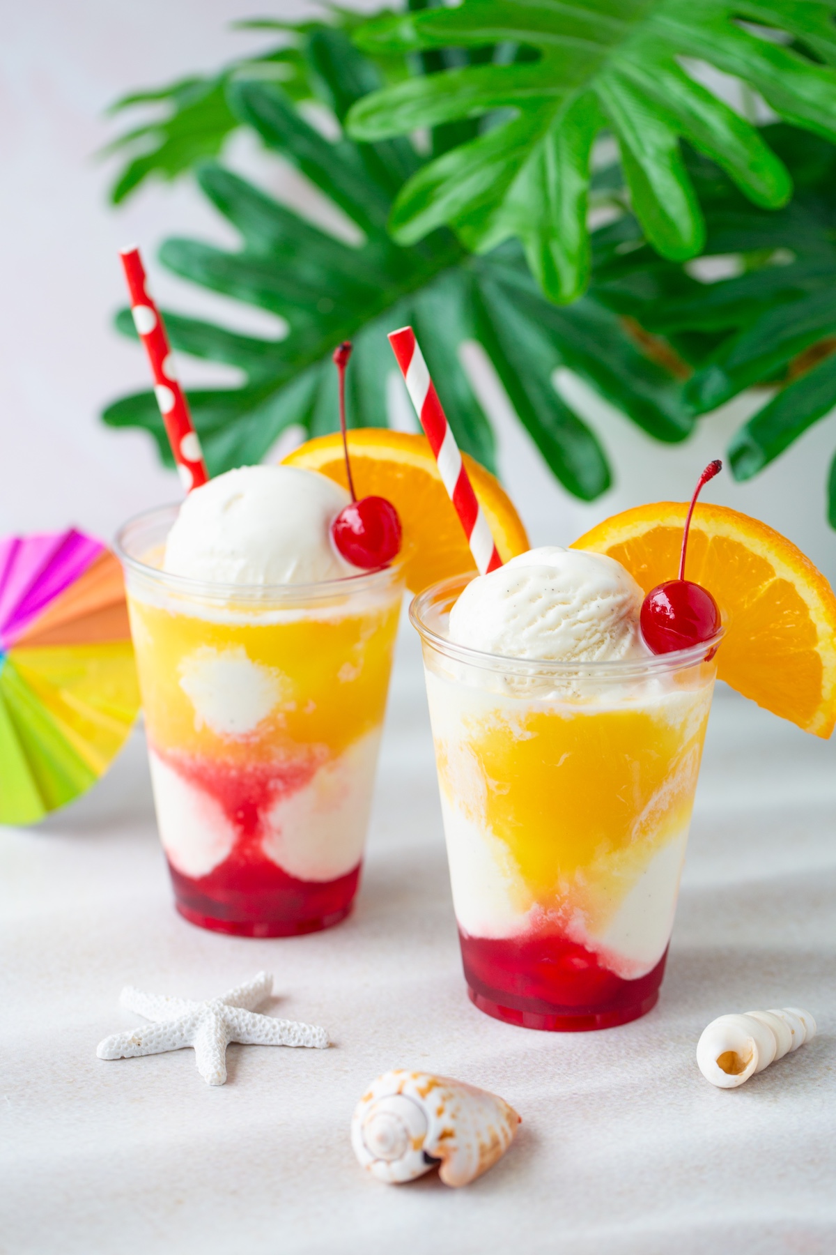 sunset floats with simple ingredients topped with cherry and orange slices as garnish.